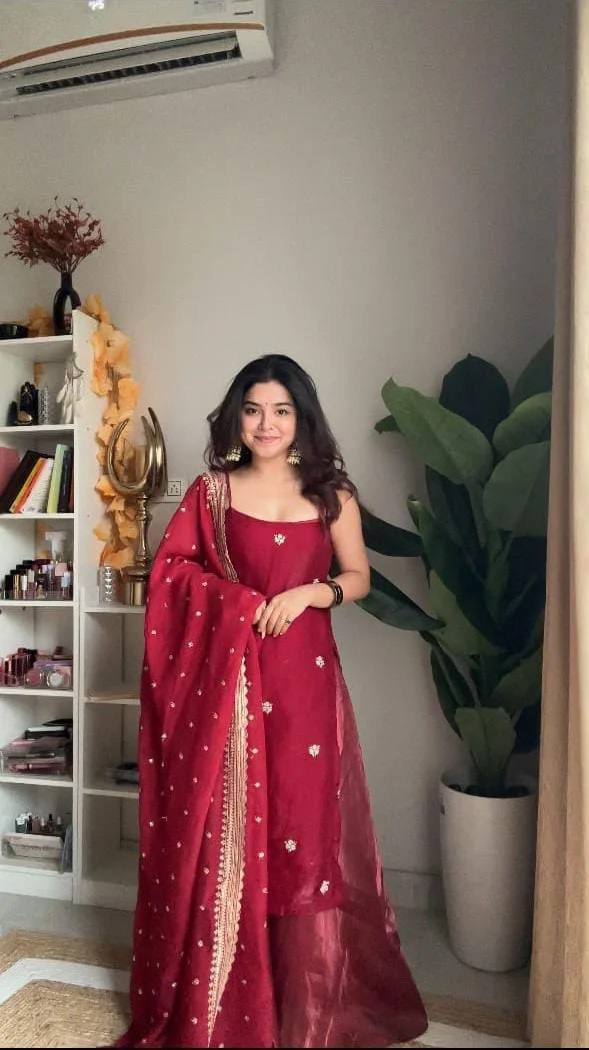 Front view model shot of a young woman wearing a maroon red noodle strap silk kurti with scattered floral bootis and a rich golden zari lace border dupatta for festive wear.